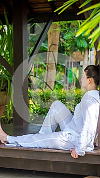 Woman wearing white clothes sitting in gazebo after practicing yoga