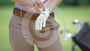 Woman wearing white golf glove before game, sport equipment and training, hobby