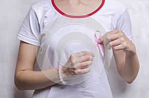Woman wearing white t-shirt, pink bangle and holding pink ribbon.Concept of medicine and healthcare photo