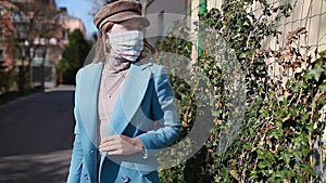 Woman wears reusable handmade mask outdoors during coronavirus covid-19 pandemic. Girl walking alone on empty street.
