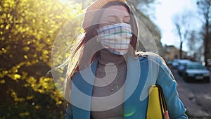 Woman wears reusable handmade mask outdoors during coronavirus covid-19 pandemic. Girl walking alone on empty street. Stay safe. S