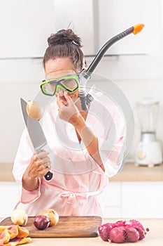 Woman wears snorkel holds her nose with one hand looking at onion stuck on a knife in the other hand