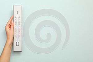 Woman with weather thermometer on light background, closeup. Space for text