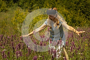 Woman weating virtual reality headset sitting in the middle of a field of flowers. Immersive VR experience