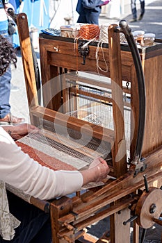 Woman weaving wool in traditional way at manual loom