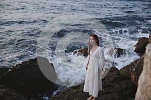 a woman in a wedding dress stands by the ocean on a cliff unaltered