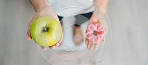 woman on weight scale and hand hold green Apple and donut, choose between fruit is Healthy and sweet is Unhealthy junk food.