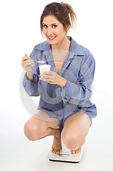 Woman on weight scales eating Healthy yogurt