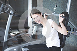 Woman weight training at gym.Exercising on pull down weight machine.Woman doing pull-ups exercising lifting dumbbells.