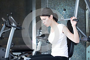 Woman weight training at gym.Exercising on pull down weight machine.Woman doing pull-ups exercising lifting dumbbells.