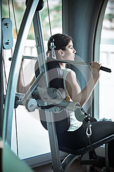 Woman weight training at gym.Exercising on pull down weight machine.Woman doing pull-ups exercising lifting dumbbells.Cardio and