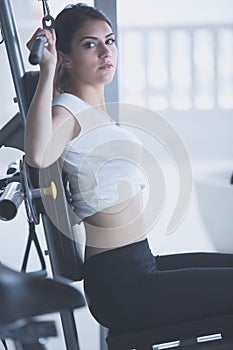 Woman weight training at gym.Exercising on pull down weight machine.Woman doing pull-ups exercising lifting dumbbells.Cardio and