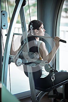 Woman weight training at gym.Exercising on pull down weight machine.Woman doing pull-ups exercising lifting dumbbells.Cardio and photo