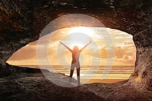 Woman welcomes the sunrise in a cave