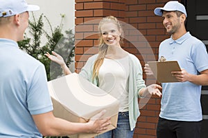 Woman welcoming professional couriers with package and receipt of delivery