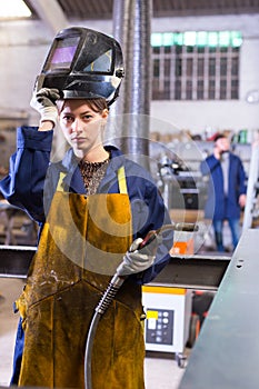 Woman welder in metalworking workshop