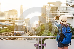 Woman westerner taking photo of sky train in city