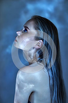 Woman with wet hair and bright makeup posing near the water, portrait. Glare from the water on the girl face, cosmetics moisturize