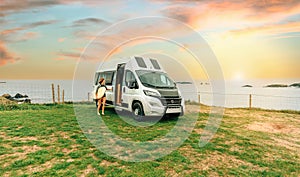 Woman with wetsuit and surfboard closing the door of her camper van to go surfing