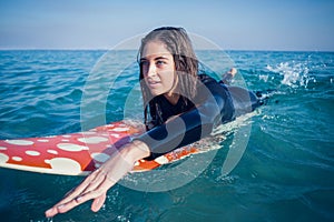 woman in wetsuit with a surfboard on a sunny day