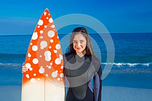 Woman in wetsuit with a surfboard on a sunny day