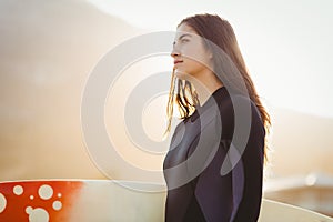 woman in wetsuit with a surfboard on a sunny day