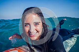 woman in wetsuit with a surfboard on a sunny day