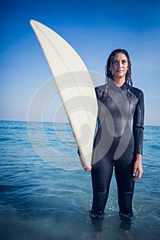 woman in wetsuit with a surfboard on a sunny day