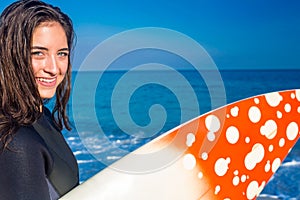 Woman in wetsuit with a surfboard on a sunny day