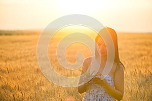 Woman with a wheat bouguet in wheat field at sunset