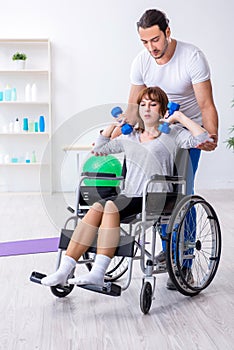 Woman in wheel-chair doing sport exercises with personal coach