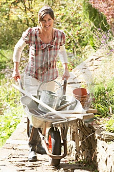 Woman With Wheelbarrow Working In Garden