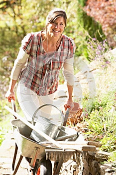 Woman With Wheelbarrow Working Outdoors In Garden
