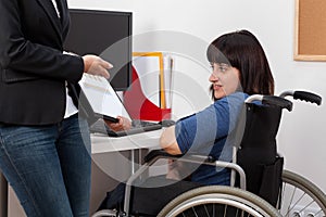 Woman on wheelchair analyzing charts with her boss