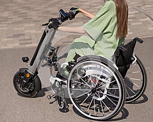 A woman in a wheelchair with an assistive device for manual control. Electric handbike.