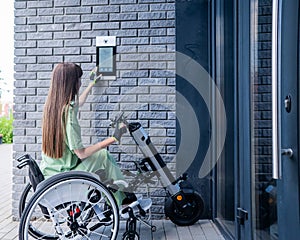 A woman in a wheelchair with an assistive device for manual control enters the entrance. Electric hand bike. photo