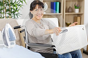 woman on wheelchair carrying basket laundry around home photo