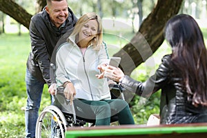 Woman in a wheelchair chats with friends in park