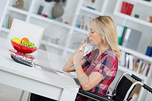 Woman in wheelchair chopping vegetables in kitchen