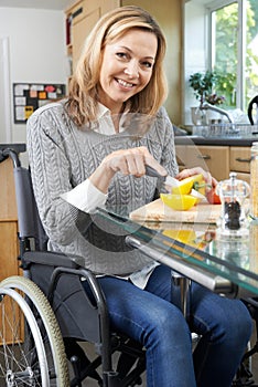 Woman In Wheelchair Chopping Vegetables In Kitchen