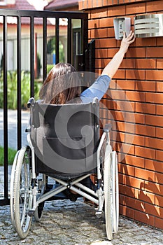 Woman on wheelchair dialing intercom