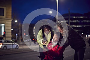 Woman In Wheelchair Having Night Out With Friends In City Ordering Taxi Using Mobile Phone App