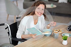 woman in wheelchair at home reading at table