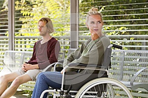 Woman in wheelchair next to young man on bench