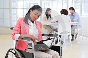 Woman in wheelchair reading document with colleauges in background photo