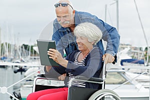 Woman in wheelchair showing tablet to husband photo