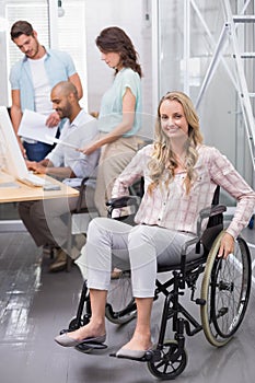 Woman in wheelchair smiling at camera with team behind her