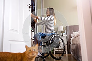 Woman in wheelchair sorts through her wardrobe