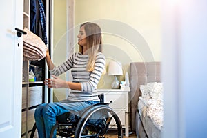 Woman in wheelchair sorts through her wardrobe