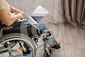 A woman in a wheelchair uses a laptop.